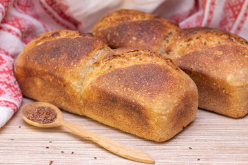 Bakery - golden rustic bread crusts. Fresh aromatic bread on the table. Food concept. wooden spoon with flax seeds.
