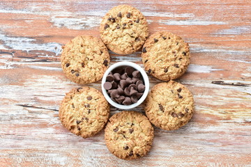 Oatmeal cookies and chocolate chips on light background