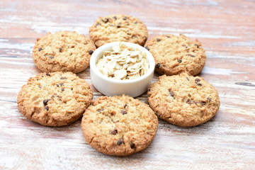 Oatmeal cookies and chocolate chips on light background