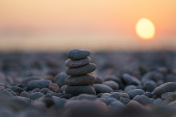 Balanced stone pyramid on pabbles beach with sunset. Zen rock, concept of balance and harmony.