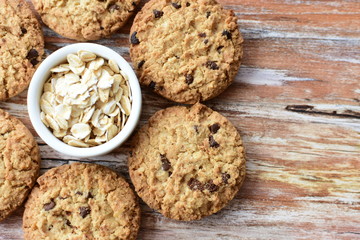 Oatmeal cookies and chocolate chips on light background
