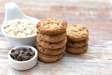 Oatmeal cookies and chocolate chips on light background