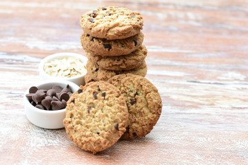 Oatmeal cookies and chocolate chips on light background