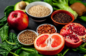 Selection of healthy food:  fruits, seeds, cereals, superfoods, vegetables, leafy vegetables on a stone background. Healthy food for humans.
