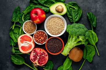 Selection of healthy food:  fruits, seeds, cereals, superfoods, vegetables, leafy vegetables on a stone background. Healthy food for humans.