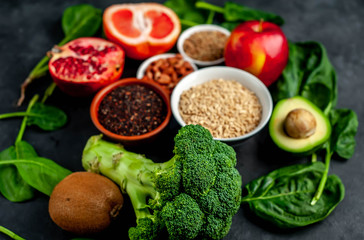 Selection of healthy food:  fruits, seeds, cereals, superfoods, vegetables, leafy vegetables on a stone background. Healthy food for humans.