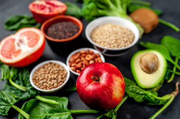 Selection of healthy food: fruits, seeds, cereals, superfoods, vegetables, leafy vegetables on a stone background. Healthy food for humans.