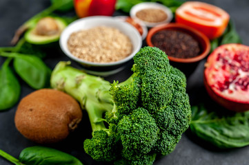 Selection of healthy food: fruits, seeds, cereals, superfoods, vegetables, leafy vegetables on a stone background. Healthy food for humans.