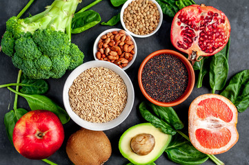 Selection of healthy food:  fruits, seeds, cereals, superfoods, vegetables, leafy vegetables on a stone background. Healthy food for humans.