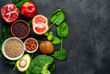 Selection of healthy food:  fruits, seeds, cereals, superfoods, vegetables, leafy vegetables on a stone background. Healthy food for humans. Copy space for your text.