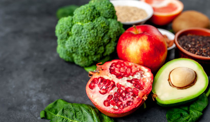 Selection of healthy food:  fruits, seeds, cereals, superfoods, vegetables, leafy vegetables on a stone background. Healthy food for humans. Copy space for your text.