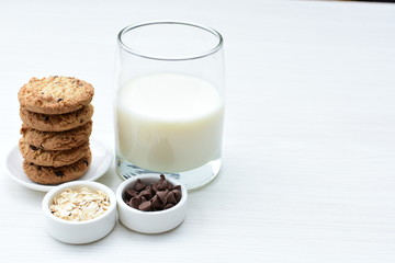 Oatmeal cookies and chocolate chips accompanied by glass of milk