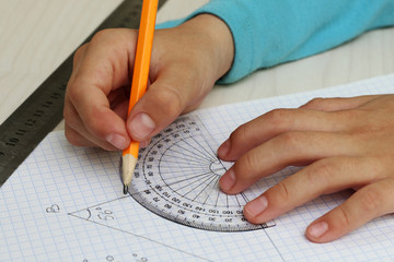 Closeup child's hands measuring angle by protractor - obrazy, fototapety, plakaty