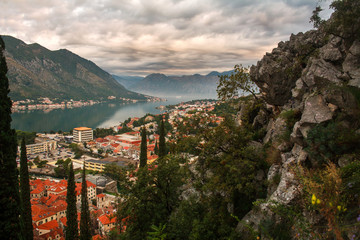 Fototapeta na wymiar Tops of roofs of the old city of Kotor on background of bay, mountains and sky