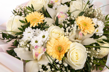 Delicate bouquet of flowers with white roses, orchids and yellow daisies.