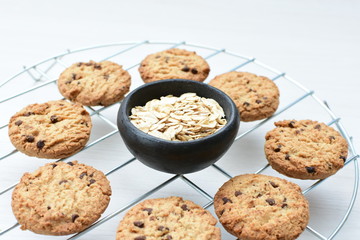 Oatmeal cookies and chocolate chips on light background