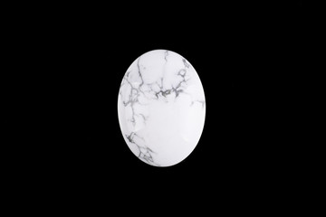 Oval cabochon stone of light color on a black background isolated