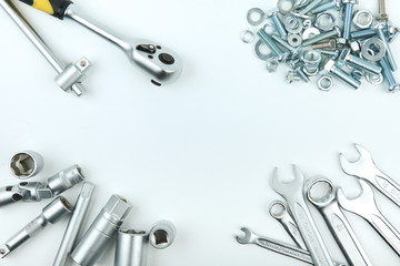 wrenches and heap of bolts and nuts on white background flat lay with copy space in the center 