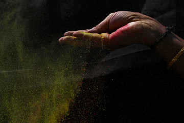Indian woman hand colourful holi powder splash at black background, Holi celebration