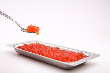 red caviar on a spoon on a white background. red caviar in a metal dish