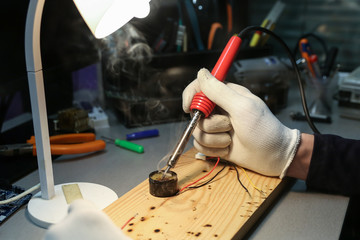 electrician hands are working with soldering iron in workshop close up
