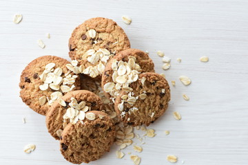 Oatmeal cookies and chocolate chips on light background