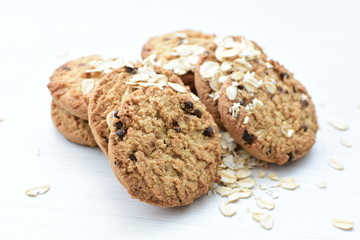 Oatmeal cookies and chocolate chips on light background