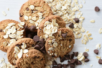 Oatmeal cookies and chocolate chips on light background