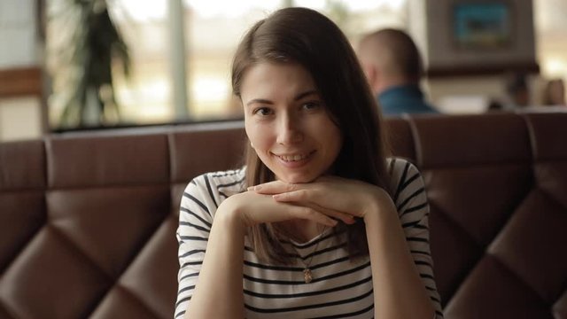 Cute woman portrait leaning head on hands sitting in cafe