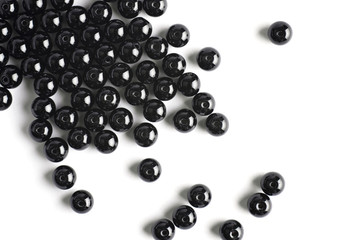Large black beads are scattered on a white isolated background
