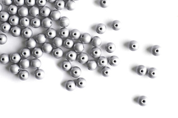 Large grey beads are scattered on a white isolated background