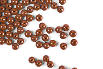 Large brown beads are scattered over a white isolated background
