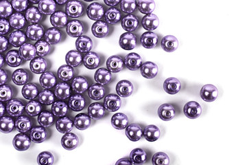 Large lilac colored beads are scattered on a white isolated background