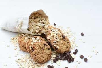 Oatmeal cookies and chocolate chips on light background