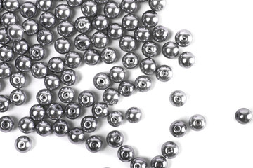 Large grey beads are scattered on a white isolated background