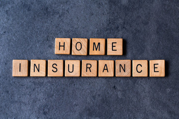 "Home Insurance" spelled out in wooden letter tiles on a dark rough background
