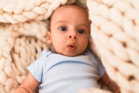 Adorable baby lying down over blanket on the sofa at home. Newborn relaxing and resting comfortable