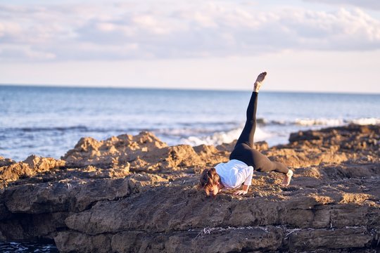 Young beautiful sportwoman practicing yoga. Coach teaching postures at the beach