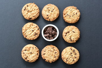 Oatmeal cookies and chocolate chips on black background