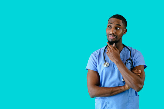 Portrait of a friendly male doctor or nurse wearing blue scrubs uniform thinking and looking to side at copy space
