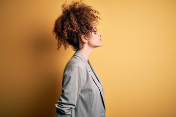 Young beautiful businesswoman with curly hair and piercing wearing elegant jacket looking to side, relax profile pose with natural face with confident smile.