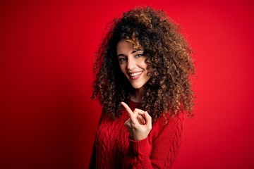 Young beautiful woman with curly hair and piercing wearing casual red sweater Beckoning come here...