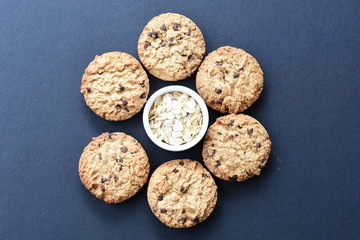 Oatmeal cookies and chocolate chips on black background