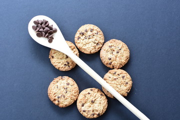 Oatmeal cookies and chocolate chips on black background