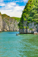Fototapeta na wymiar Halong bay islands. Tourist attraction, spectacular limestone grottos natural cave formations. Karst landforms in the sea, the world natural heritage. Beautiful azure water of the lagoon. Boat sail