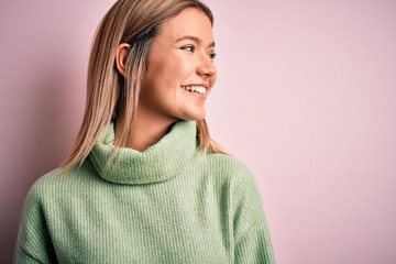 Obraz premium Young beautiful blonde woman wearing winter wool sweater over pink isolated background looking away to side with smile on face, natural expression. Laughing confident.