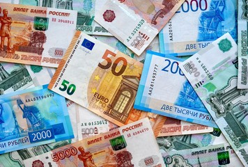Euro banknote on top of russian national currency, top view of mixed rouble banknotes. Rubles and euro exchange rate