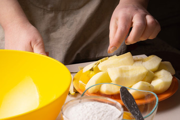 Hands of an elderly woman peeling an apple with a white ceramic knife.