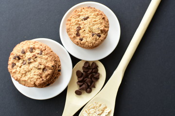 Oatmeal cookies and chocolate chips on black background