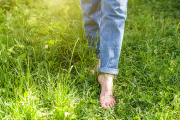 Two beautiful female feet walking on grass in sunny summer morning. Light step barefoot girl legs...